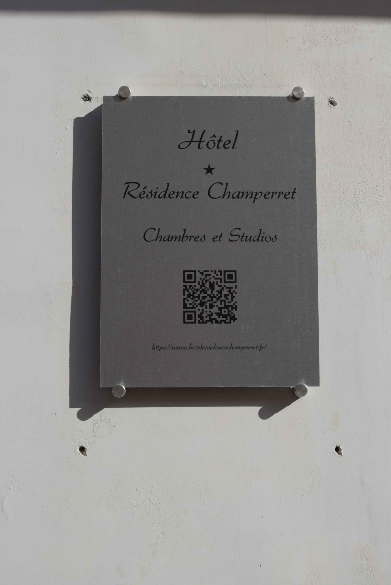 Hotel plaque reading Chambres et Studios with a QR code to the website