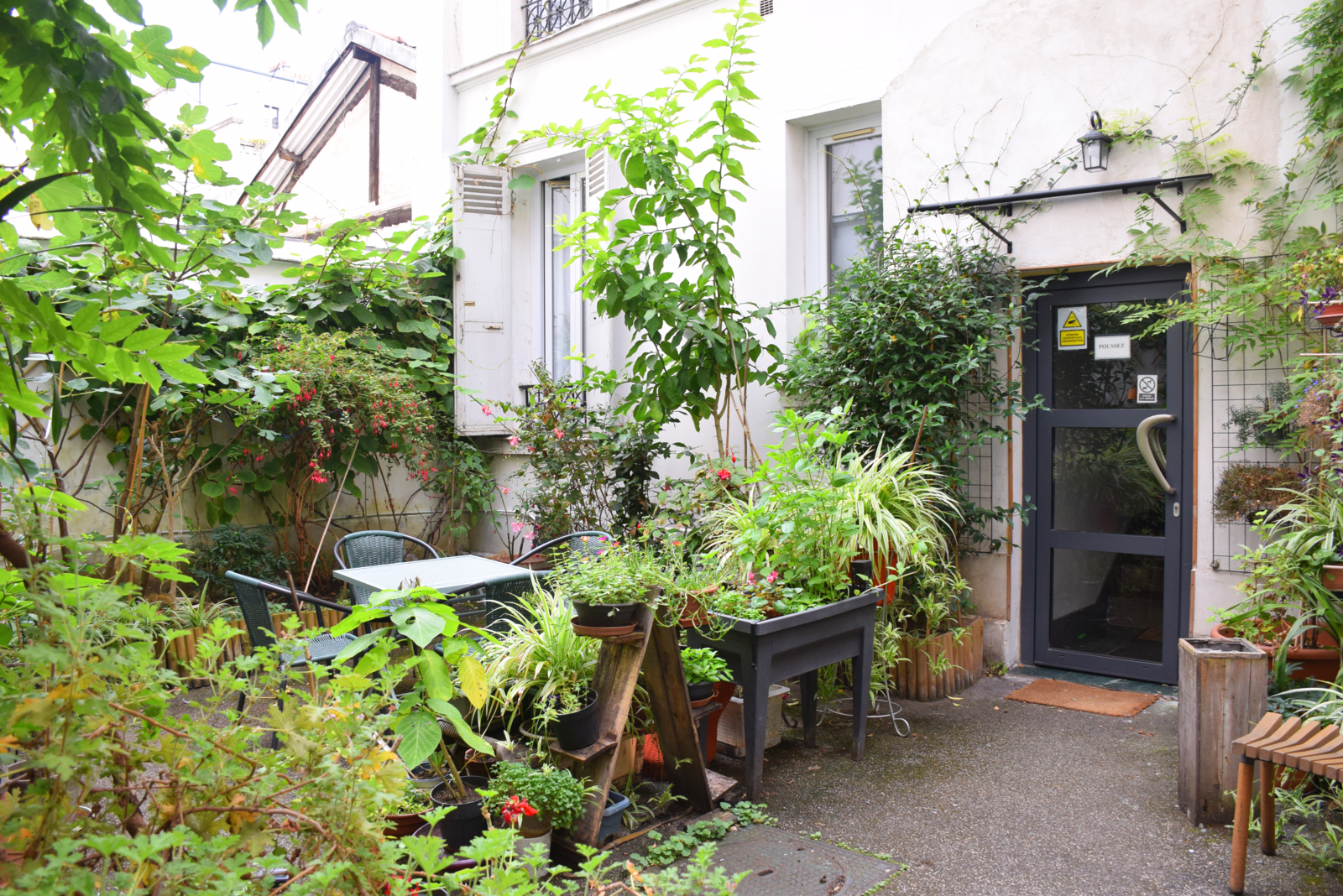 Lush garden at Hôtel Résidence Champerret with table and chairs surrounded by plants and flowers